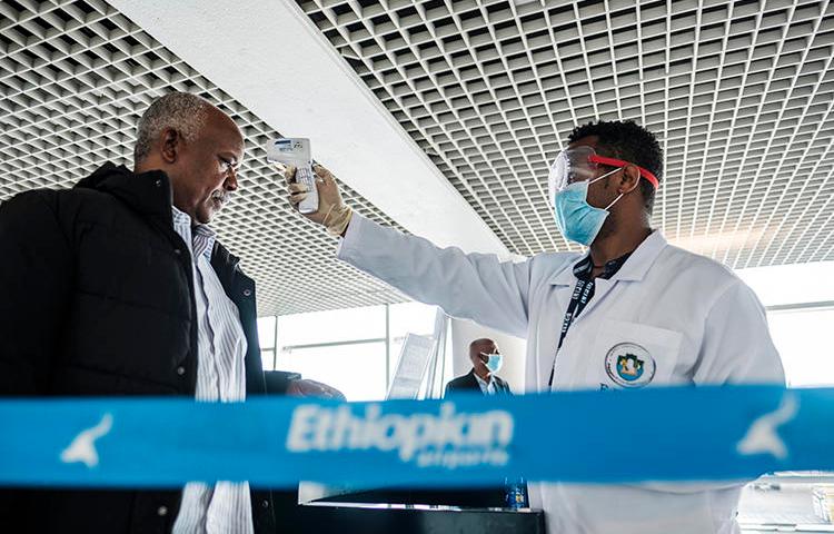 A worker of the Ethiopian Public Health Institute measures a man's temperature in Addis Ababa, on March 17, 2020. Ethiopian police are holding journalist Yayesew Shimelis pending a terrorism investigation. (AFP/Eduardo Soteras)