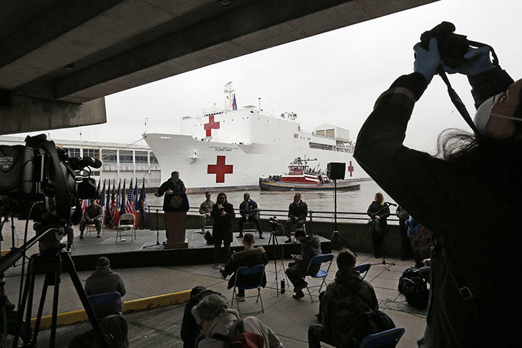 A journalist records a press briefing following the arrival of the USNS Comfort, a naval hospital ship with a 1,000 bed-capacity at Pier 90 in New York, on March 30, 2020. (AP Photo/Kathy Willens, File)