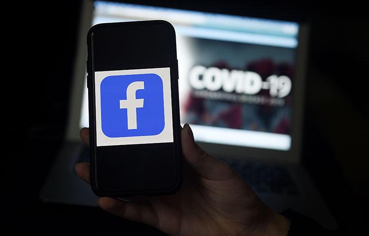 The Facebook logo is displayed on a mobile phone screen photographed on a COVID-19 illustration graphic background on March 25, 2020 in Arlington, Virginia. CPJ and partners called on social media and content sharing platforms to preserve data amid the pandemic. (AFP/Olivier Douliery)
