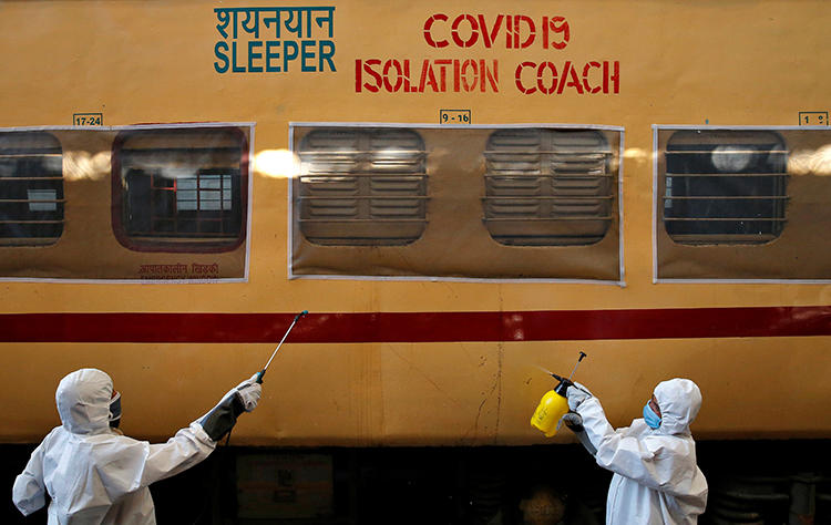 Workers wearing protective suits disinfect a passenger train on the outskirts of Kolkata, India, on April 6, 2020. Indian freelance journalist Vidya Krishnan recently spoke with CPJ about the challenges of covering the COVID-19 pandemic. (Reuters/Rupak De Chowdhuri)