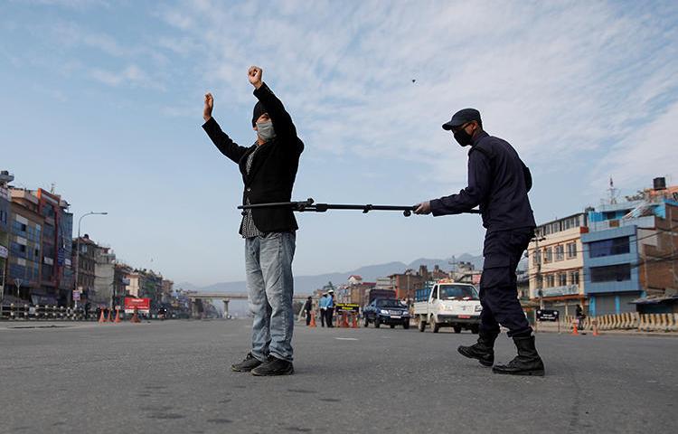 A Nepalese police officer maintains distance as he detains a man defying the lockdown imposed by the government amid concerns about the spread of coronavirus disease (COVID-19), in Kathmandu on March 29, 2020. Several journalists have been detained or obstructed while reporting since the lockdown was imposed. (Reuters/Navesh Chitrakar)