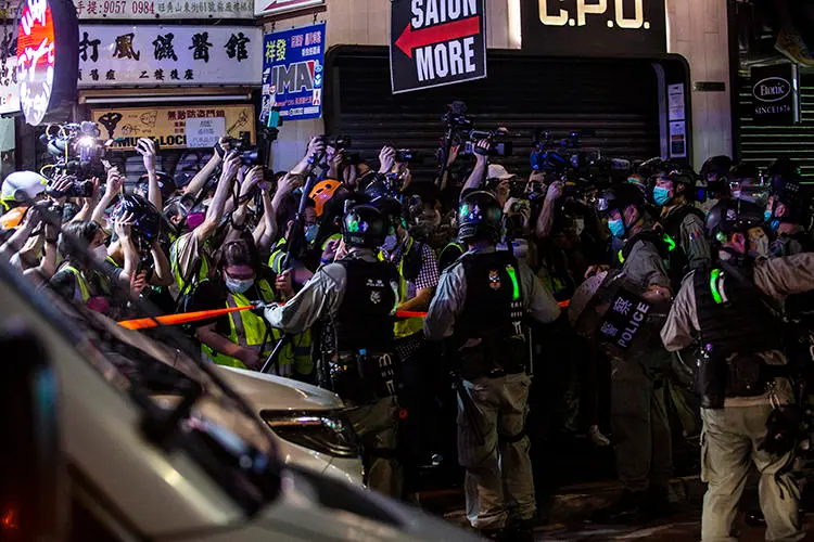 Riot police hold back members of the press in the Mong Kok district of Hong Kong on May 10, 2020. Police attacked and arrested journalists covering that protest. (AFP/Isaac Lawrence)