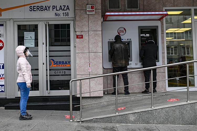 21 Nisan 2020 günü çekilen bu fotoğrafta İstanbul’da bir bankanın önündeki insanlar görülüyor. Türkiye kısa süre önce ekonomi haberciliğini kısıtlayabilecek bir finans yönetmeliğini yürürlüğe koydu. (AFP/Ozan Köse)