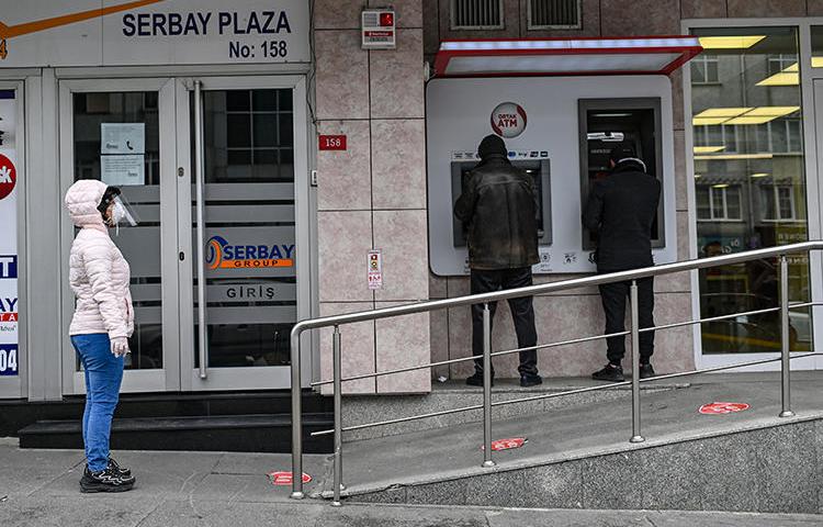 People are seen outside a bank in Istanbul, Turkey, on April 21, 2020. Turkey recently passed a financial regulation that may restrict economic reporting. (AFP/Ozan Kose)