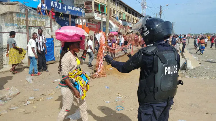 A police officer clears shoppers from a market on the first day of lockdown to stop the spread of COVID-19 disease in Monrovia, Liberia, on April 11, 2020. The government says the right to free expression is suspended during the state of emergency. (Reuters/Derick Snyder)