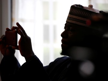 A man is shown in profile against a window holding a camera up to take a photo.