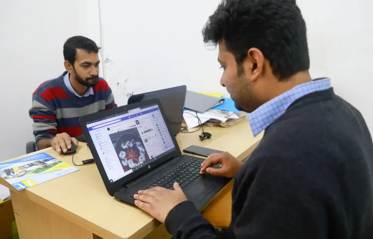 Two men use laptops on opposite sides of a desk