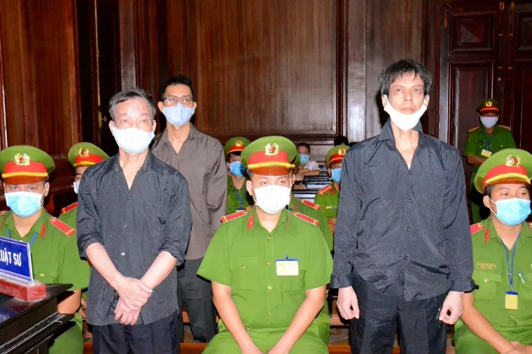 Journalists Nguyen Tuong Thuy (left), Pham Chi Dung (right), and Le Huu Minh Tuan (back) are seen at a courthouse in Ho Chi Minh city, Vietnam, on January 5, 2021. The three were each sentenced to more than 10 years in prison. (Vietnam News Agency/AFP)