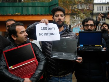 A group of men are pictured holding powered off laptops and a placard reading "100 days no internet."