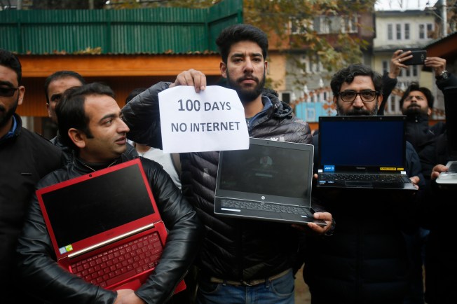 A group of men are pictured holding powered off laptops and a placard reading "100 days no internet."