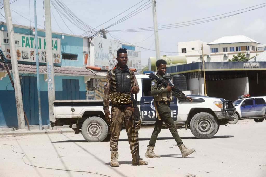 Two armed police officers in fatigues stand guard near the scene of a militant attack in Mogadishu, Somalia August 21, 2022.