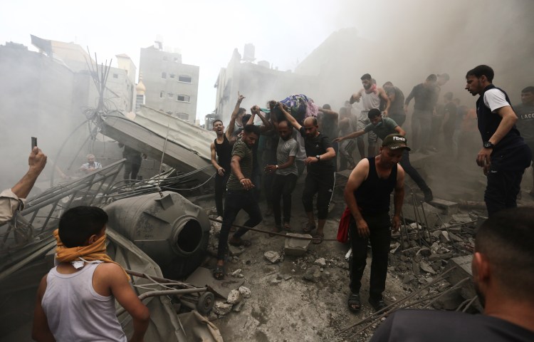 Palestinians remove a dead body from the rubble of a building after an Israeli airstrike Jebaliya refugee camp, Gaza Strip, on October 9, 2023. (AP Photo/Ramez Mahmoud)