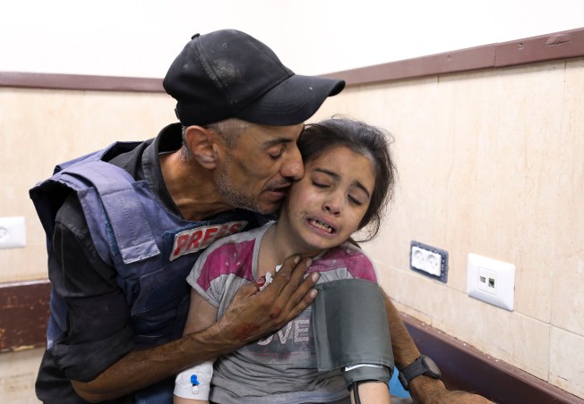 A Palestinian journalist comforts his niece, who was wounded in an Israeli strike on her family home at a refugee camp in the Gaza Strip on October 22.