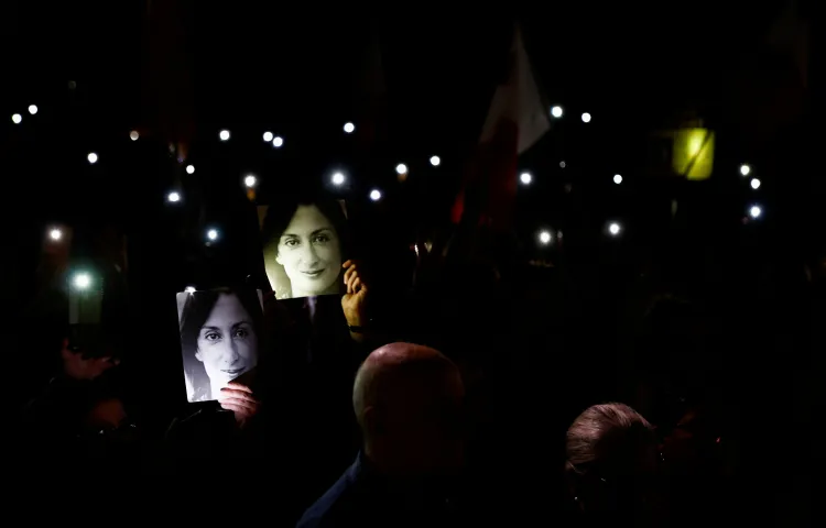 People hold up their phones with their flashes on after a protest march on the fifth anniversary of the assassination of journalist Daphne Caruana Galizia in Valletta, Malta, on October 16, 2022.