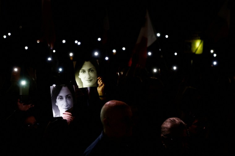 People hold up their phones with their flashes on after a protest march on the fifth anniversary of the assassination of journalist Daphne Caruana Galizia in Valletta, Malta, on October 16, 2022.