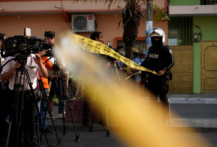 Journalists stand behind a police tape at a crime scene in Guayaquil, Ecuador, on November 1, 2022.