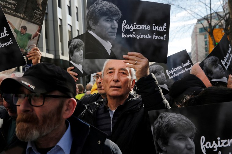 A man in a crowd holds up a placard with a photograph of slain journalist Hrant Dink at a demonstration to mark the 16th anniversary of his murder in Istanbul, Turkey, on January 19, 2023.