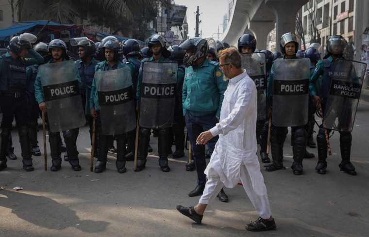 A man walks past policemen in riot gear ahead of elections in Dhaka, Bangladesh, on January 5, 2024.