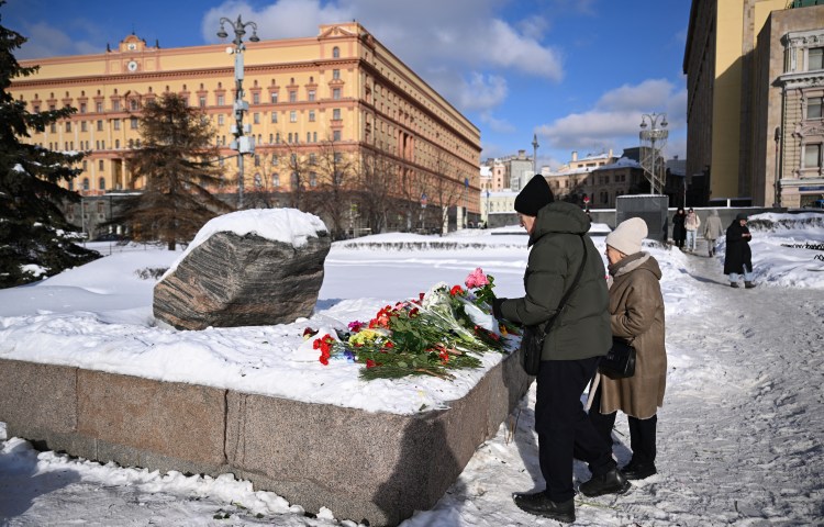 People lay flowers for late Russian opposition leader Alexei Navalny at the Solovetsky Stone, a monument to political repression, near the headquarters of Russia's Federal Security Services, in Moscow on February 20, 2024. (AFP/Natalia Kolesnikova)