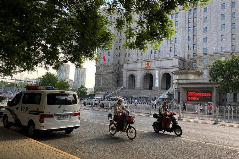 People ride past a police van outside the No. 2 Intermediate People's Court ahead of Australian writer Yang Hengjun's espionage trial in Beijing, May 27, 2021. (Photo: AP/Andy Wong)