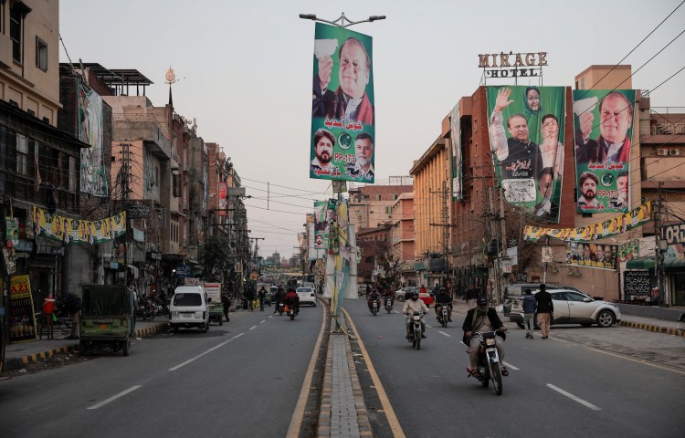 People commute on a street filled with election campaign banners and posters in Lahore, Pakistan, on February 5, 2024.