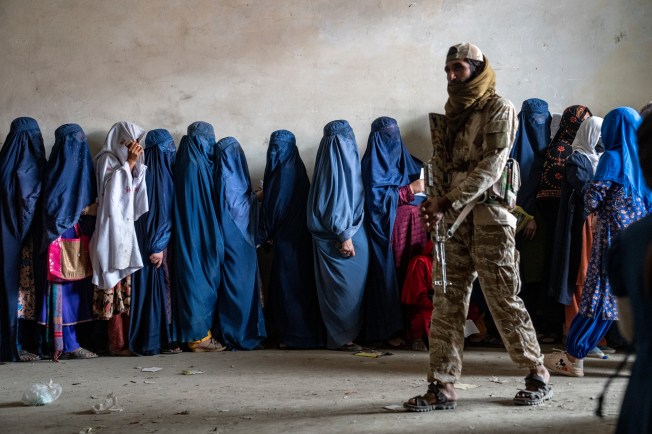 A Taliban fighter stands guard as women wait for humanitarian aid in Kabul, Afghanistan, in May 2023.