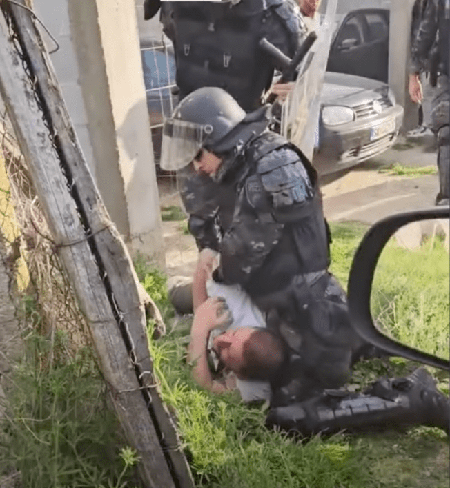 A police officer holds journalist Furkan Saliu down on the ground at a soccer game in Gorno Konjare in North Macedonia on April 7.