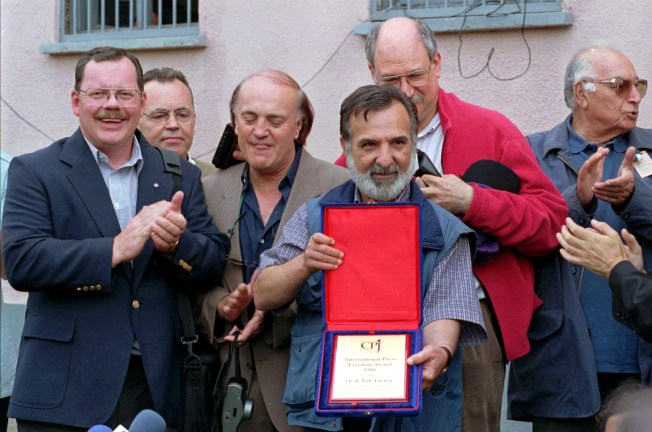 Terry Anderson presents Turkish editor Ocak Isik Yurtcu with a CPJ International Press Freedom Award in July 1997 at the prison where Yurtcu was held. Yurtcu, who had been imprisoned since 1994, was freed one month after receiving the award. Attendees at the event included (front row, left to right), CNN correspondent Peter Arnett, Yurtcu, Newsday correspondent Josh Friedman, Yurtcu and Turkish novelist, Yasar Kemal. Turkish reporter Yalcin Bayer is seen behind Anderson. (Photo: AP/Murad Sezer)