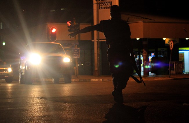 An officer stands guard in the dark with a rifle.