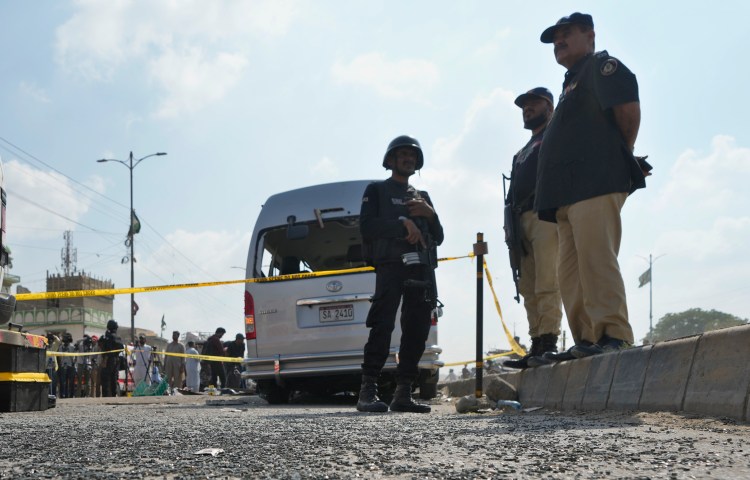 Police officers stand guard at the site of a suicide attack in Karachi, Pakistan, in April 2024.
