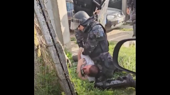 A police officer holds journalist Furkan Saliu down on the ground at a soccer game in Gorno Konjare in North Macedonia on April 7.