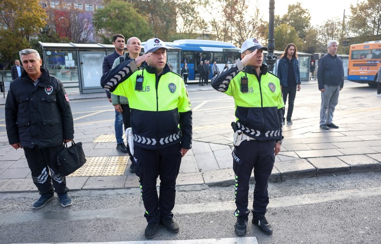 Two police officers salute in front of a group of people.
