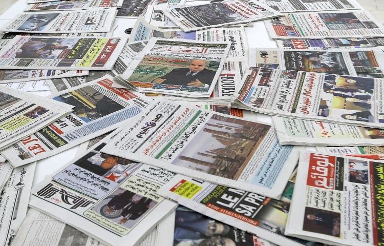 A collection of newspapers spread on a table.