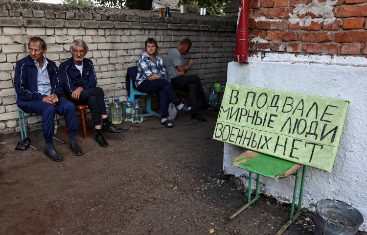 Local Russian residents sit near a shelter in the town of Sudzha on August 16, 2024, where Italian journalists Stefania Battistini and Simone Traini were shown in a report speaking to residents and looking at damaged houses and cars. (Photo: Reuters/Yan Dobronosov)