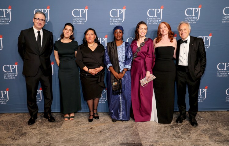 Honorees (beginning third from left) Quimy de Leon, Samira Sabou, and Alsu Kurmasheva, attend CPJ's 2024 International Press Freedom Awards event on November 21 in New York City, along with host John Oliver (left), Perrine Daubas, accepting a posthumous award for her husband, Christophe Deloire, (second from left), CPJ CEO Jodie Ginsberg (second from right), and CPJ Board Chair Jacob Weisberg. Awardee Shrouq Al Aila was not allowed to leave Gaza to attend the event. (Photo: Dia Dipasupil/Getty Images)