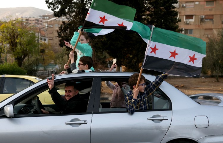 People celebrate with the Syrian opposition flag in Damascus on December 10, 2024, after Bashar al-Assad's oppressive regime was toppled and the former president fled to Russia. (Photo: AFP/Omar Haj Kadour)