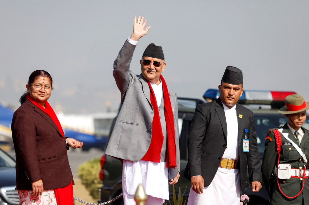 Nepal's Prime Minister Khadga Prasad Sharma Oli waves alongside his wife Radhika Shakya before their departure from the airport in Kathmandu on December 2, 2024. (Photo: AFP/Aryan Dhimal)