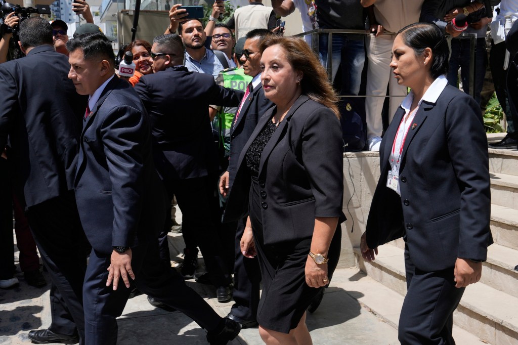 Peruvian President Dina Boluarte, center, is surrounded by security as she leaves the home of the late Peruvian Nobel literature laureate Mario Vargas Llosa, where she gave her condolences to his family the day after his death, in Lima, Peru, Monday, April 14, 2025. (AP Photo/Martin Mejia)