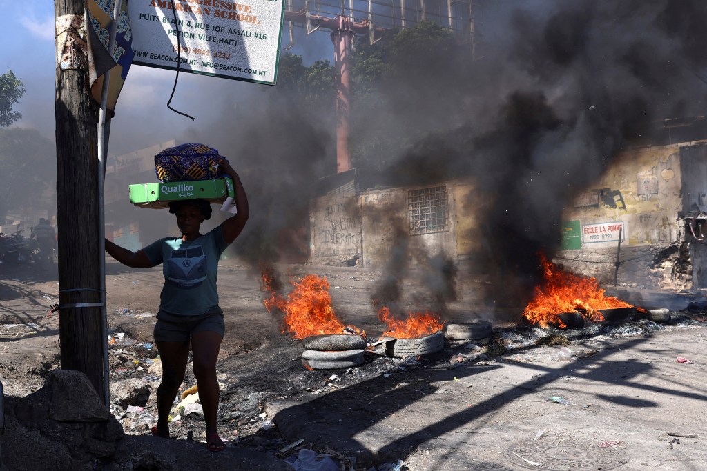 A woman walks past a burning barricade set during a protest in Port-au-Prince, Haiti on April 2, 2025. Violence against journalists is increasing as Haiti descends further into chaos. (Photo: Reuters/Ralph Tedy Erol)