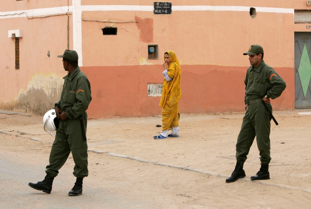 A Sahrawi woman walks near Moroccan police in Laayounne in the disputed territory of Western Sahara in 2005.