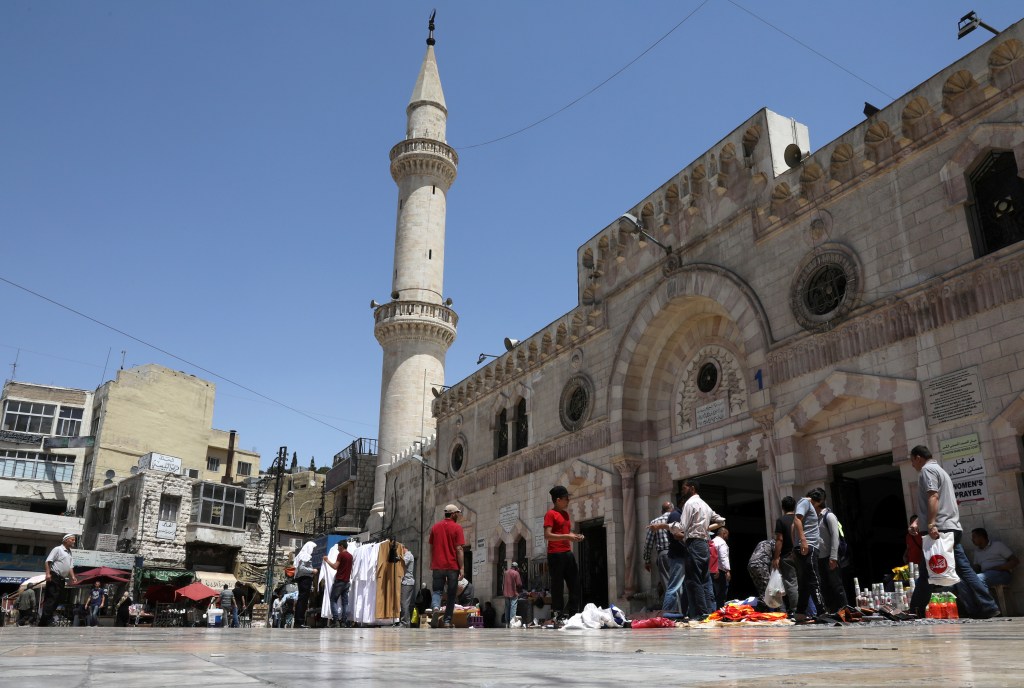 People walk past street vendors outside a mosque in Amman, Jordan, in 2018.