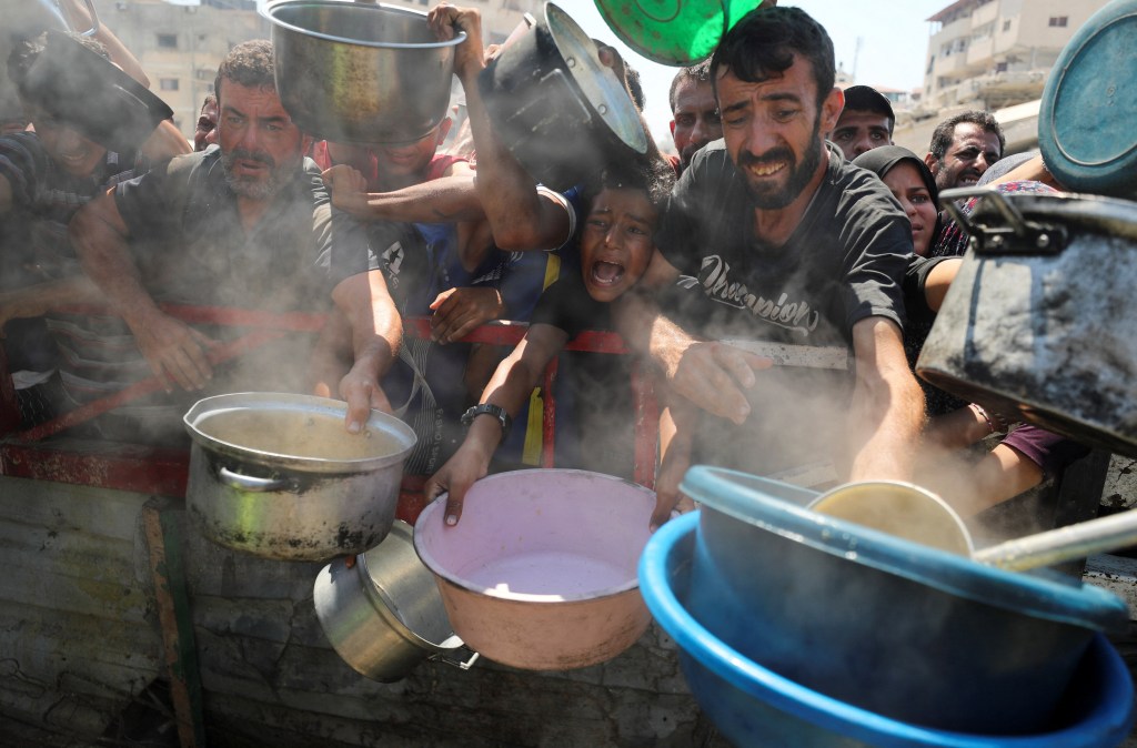 Palestinians wait to receive food from a charity kitchen in Gaza City on July 23, 2025.