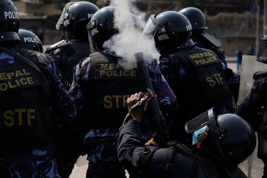 A Nepalese policeman fires tear gas as Nepalese protesters opposing a proposed U.S. half-billion dollars grant for Nepal clash with police outside the parliament in Kathmandu, Nepal, Thursday, Feb. 24, 2022. Hundreds of protesters against the US grant gathered outside the parliament clashed with riot police, who have lined up and set up barricades as lawmakers were scheduled to begin debate on the grant proposal Thursday. (AP Photo/Niranjan Shrestha)