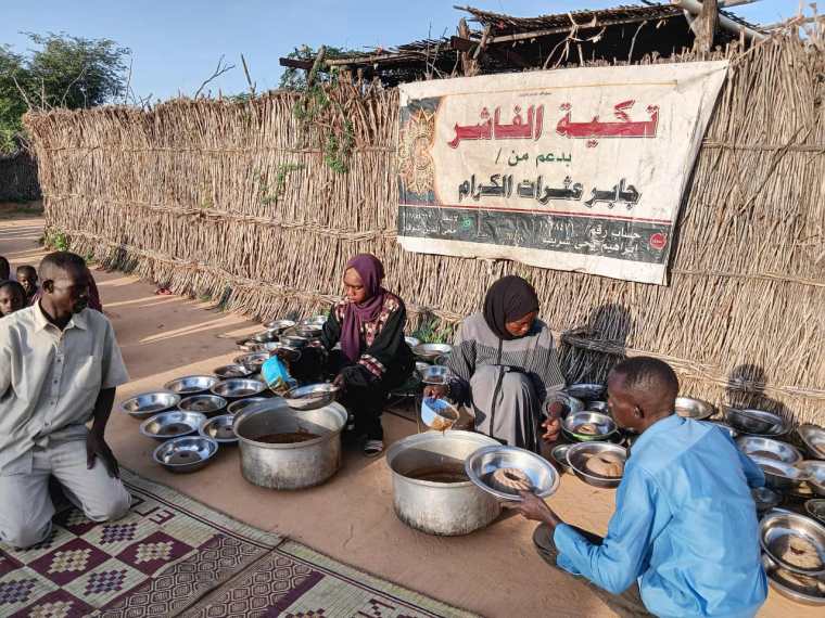 Residents of El-Fasher gather at a communal kitchen to receive what little food is still available in the besieged city.