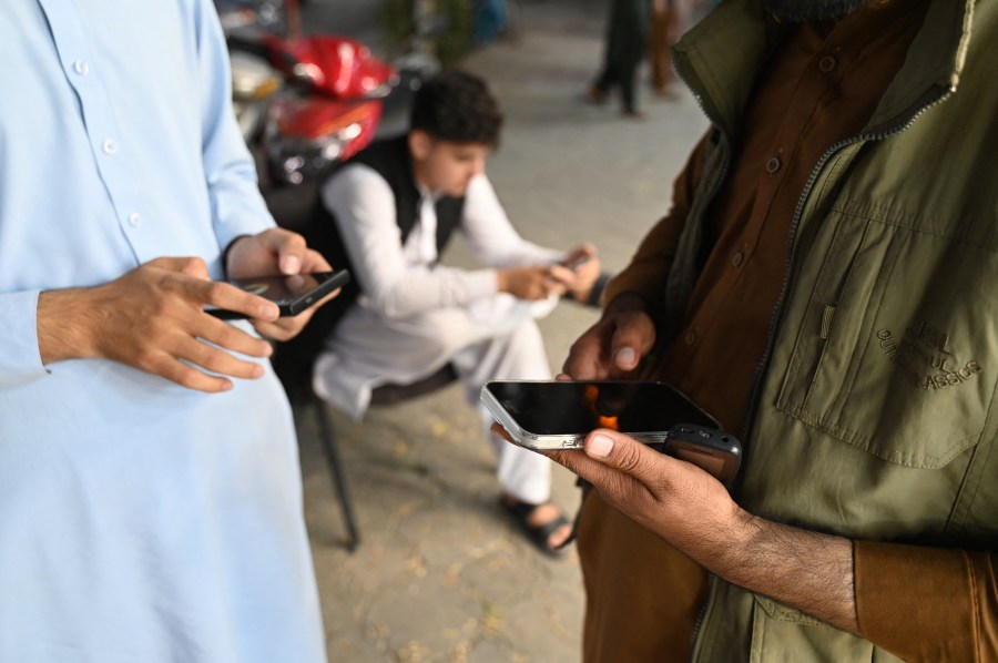 Afghan men use their mobile phones in Kabul on October 1, 2025.