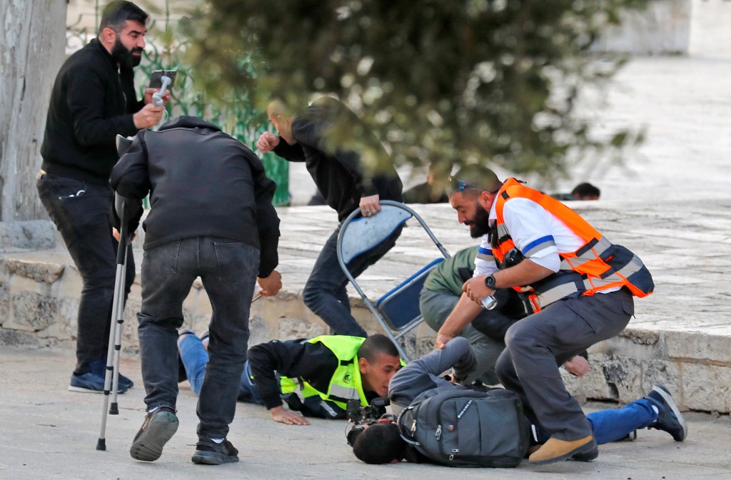 Crescent medics assist an injured journalist amid clashes between Israeli security forces and Palestinians at the Al-Aqsa Mosque complex in 2022.