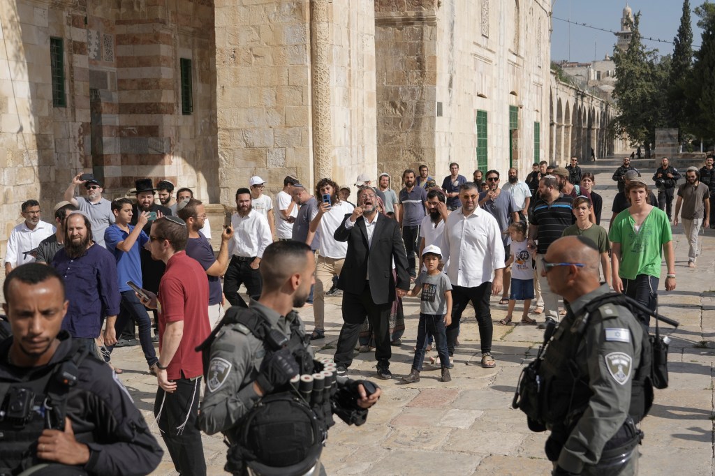 Israeli police officers escort lawmaker Itamar Ben-Gvir, center, and a group of Jewish men as they visit the Temple Mount, known to Muslims as the Noble Sanctuary, on the Al-Aqsa Mosque compound in the Old City of Jerusalem, during the annual mourning ritual of Tisha B'Av (the ninth of Av) a day of fasting and a memorial day, commemorating the destruction of ancient Jerusalem temples, Sunday, Aug. 7, 2022.