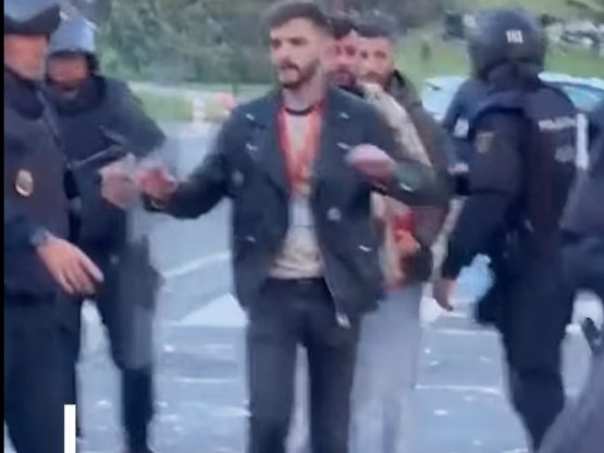 After a violent assault by masked protesters, journalist José Ismael Martínez reaches riot police for protection during clashes in Pamplona on October 30, 2025.