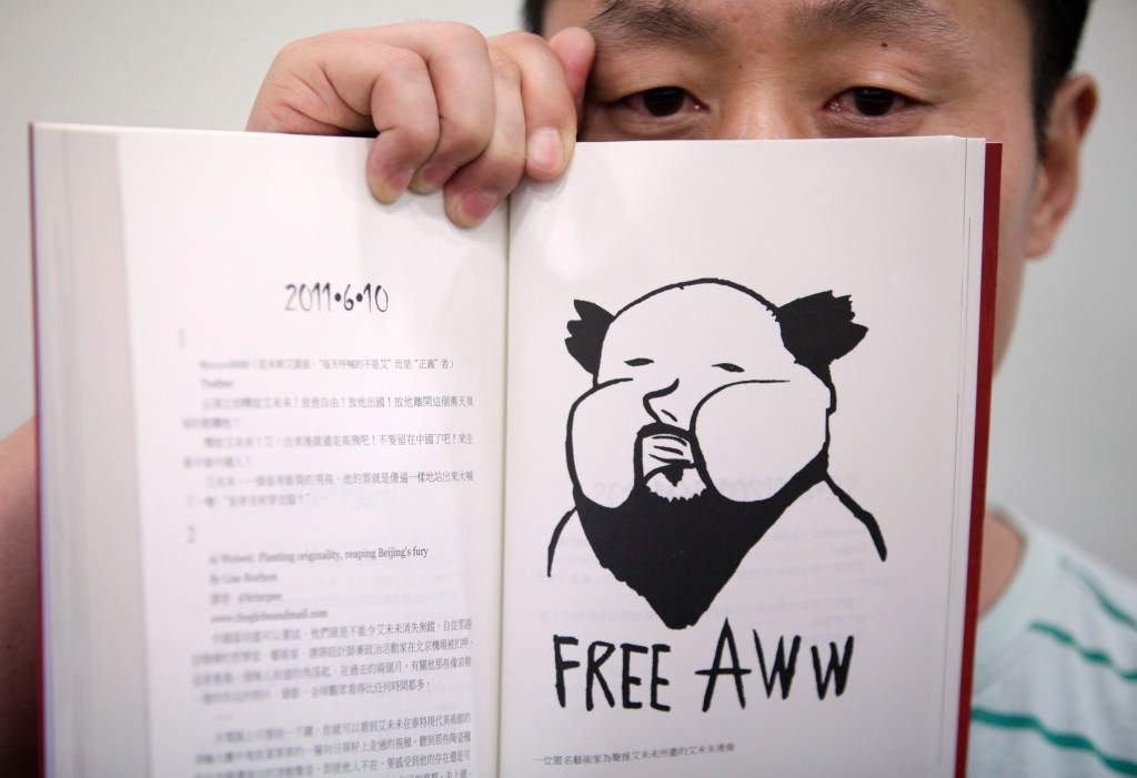 Chinese journalist Du Bin poses with his book “God Ai,” said to be the first biography of Ai Weiwei