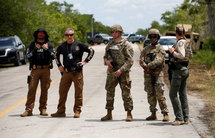 Members of the Florida National Guard and law enforcement officers monitor a protest at an entrance road of a temporary migrant detention center nicknamed "Alligator Alcatraz" on the day of a visit by U.S. President Donald Trump in Ochopee, Florida, U.S., July 1, 2025. REUTERS/Octavio Jones